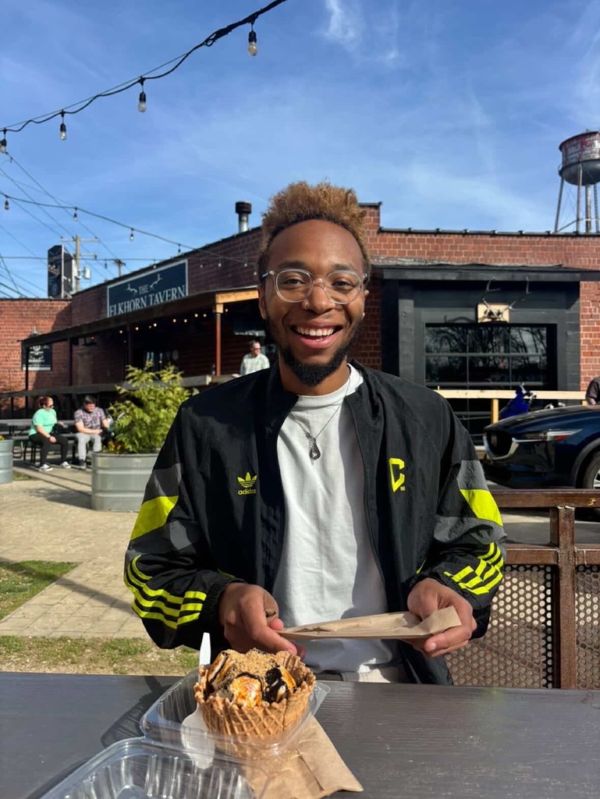 Malik smiling over a waffle-bowl sundae outside the Elkhorn Tavern